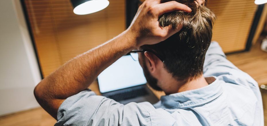 Young stressed businessman in a panic in front of a computer in office.